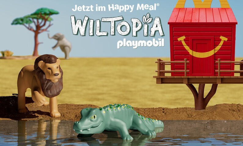 Kinderspielset aus Löwe am Wasser und Krokodil auf Erde, buntes Baumhaus im Hintergrund. | © McDonald's Deutschland